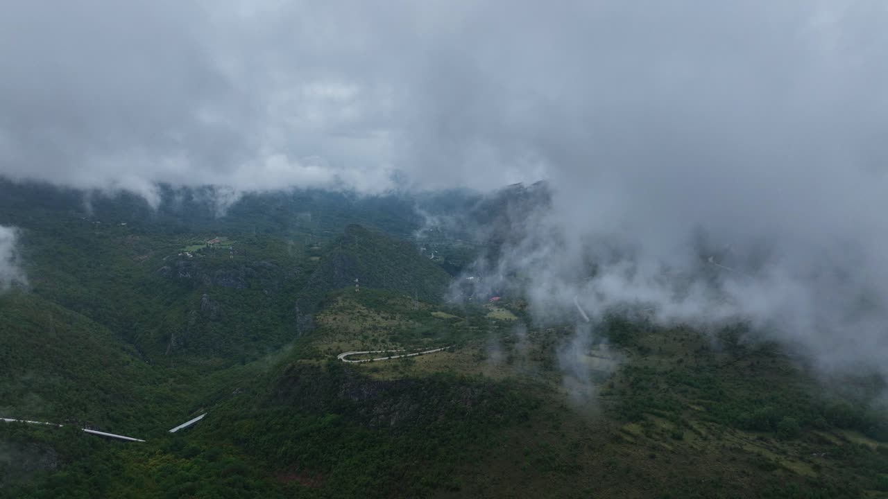 Aerial: mountains, trees and clouds during the day in a rural zone near Cetinje, Montenegro, orbit drone shot