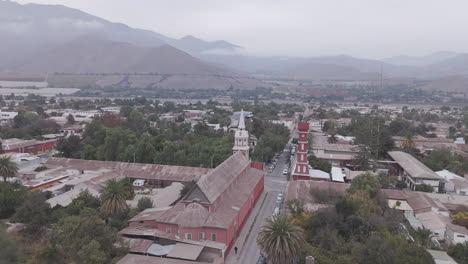spiral drone shot around the town of vicuña near coquimbo in chile south america with the main square and red tower torre bauer visible on a grey day with mountains in the background log
