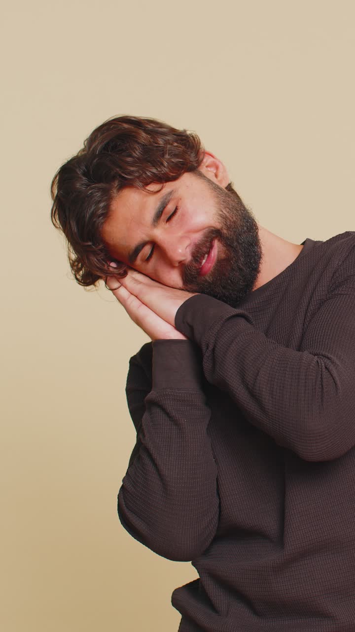 Tired overworked man yawning sleepy feeling bored suffering from lack of sleep on beige background