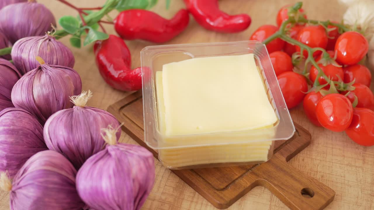 queso, ajo y tomates en una tabla de cortar de madera