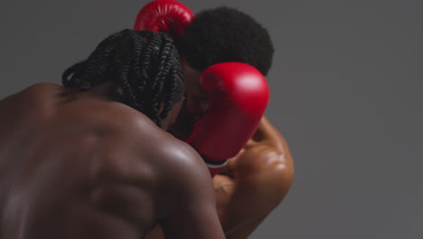 toma de estudio de cerca de dos boxeadores masculinos con guantes luchando en un partido de boxeo contra un fondo gris 9