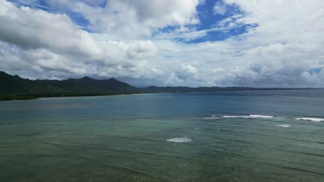 Stunning-aerial-view-of-island-landscape-with-ocean-waves-crashing-against-reef-and-breathtaking-cloudscape