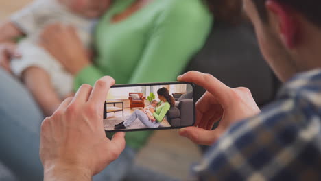 Aufnahme-Aus-Der-Sicht-Eines-Vaters,-Der-Ein-Foto-Einer-Mutter-Macht,-Die-Mit-Ihrem-Kleinen-Sohn-Auf-Dem-Mobiltelefon-Spielt