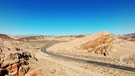 California-Highway-58-through-the-Mojave-Desert-and-the-iconic-red-rock-cliffs-and-buttes---sliding-aerial-flyover