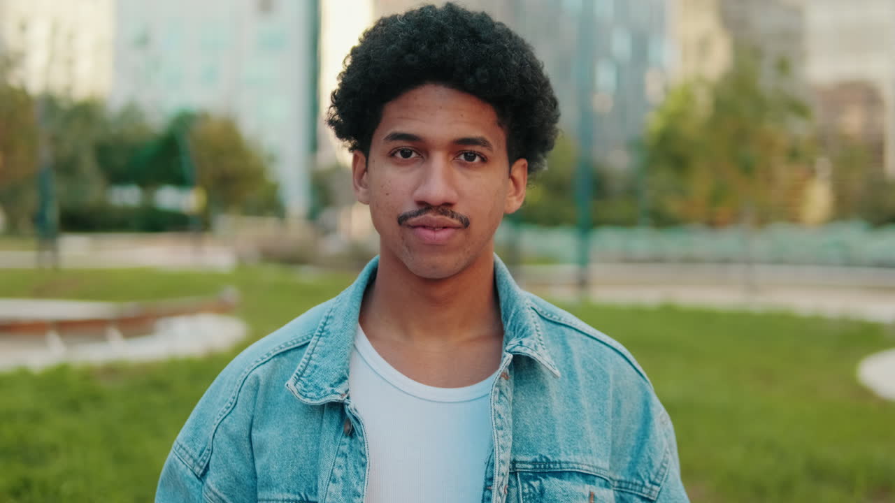 Retrato de um homem com cabelo cacheado e jaqueta jeans ao ar livre
