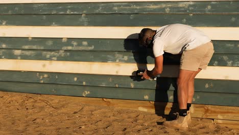 carpenter fixing beach hut wall with tools