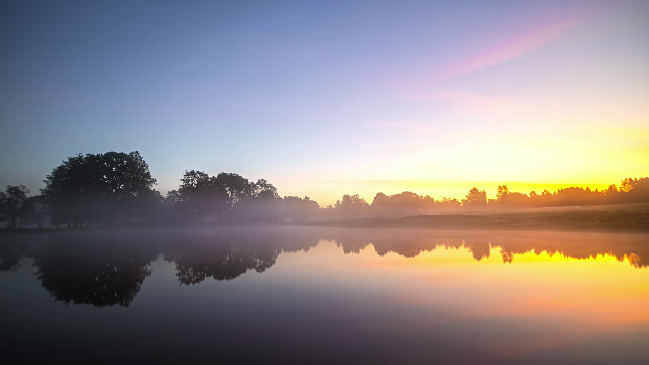 Timelapse showcasing a rural landscape with a serene lake and house transitioning through the four seasons featuring snow, colorful leaves, misty mornings, and vibrant sunrises and sunsets