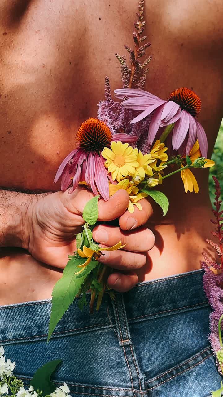 hombre sosteniendo flores silvestres detrás de su espalda