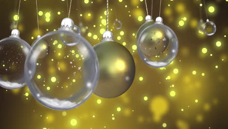 animation of glass baubles over snow falling on yellow background