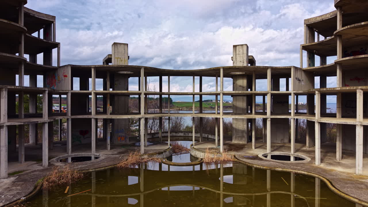 Esplorando la bellezza inquietante di una struttura in cemento abbandonata in riva a un lago sereno sotto un cielo cupo