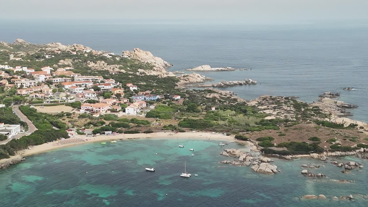 Vista di una città costiera in Sardegna con barche nell'acqua cristallina