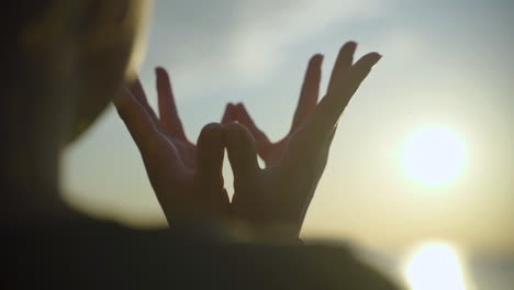 silhouette of woman's hands in padma mudra beside the lake at sunrise.