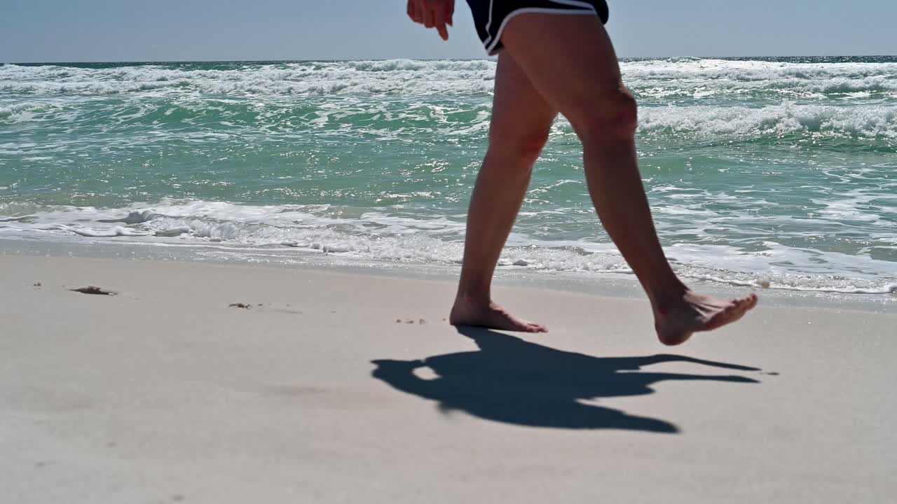 Donne che camminano sulle spiagge di sabbia bianca con acque limpide color smeraldo e onde nel Golfo del Messico in una luminosa giornata estiva di sole
