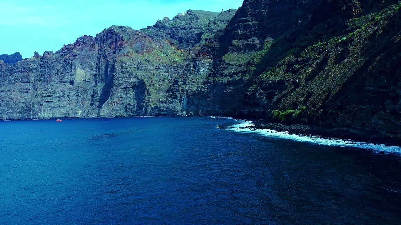 스페인 테네리페 섬의 높은 산 아래 부드러운 파도가 있는 푸른 바닷물