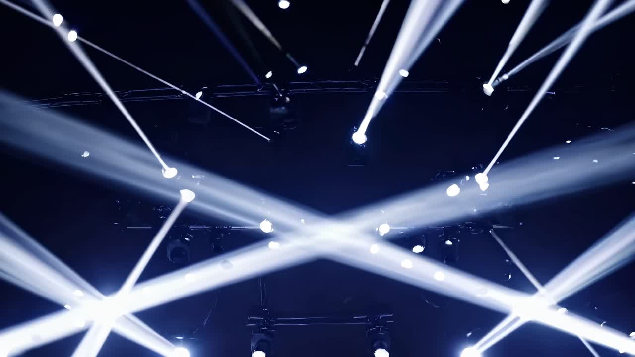 Dynamic video scene with a low-angle view of bright spotlights piercing a dark space