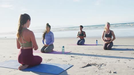 grupo de diversas amigas meditando en la playa