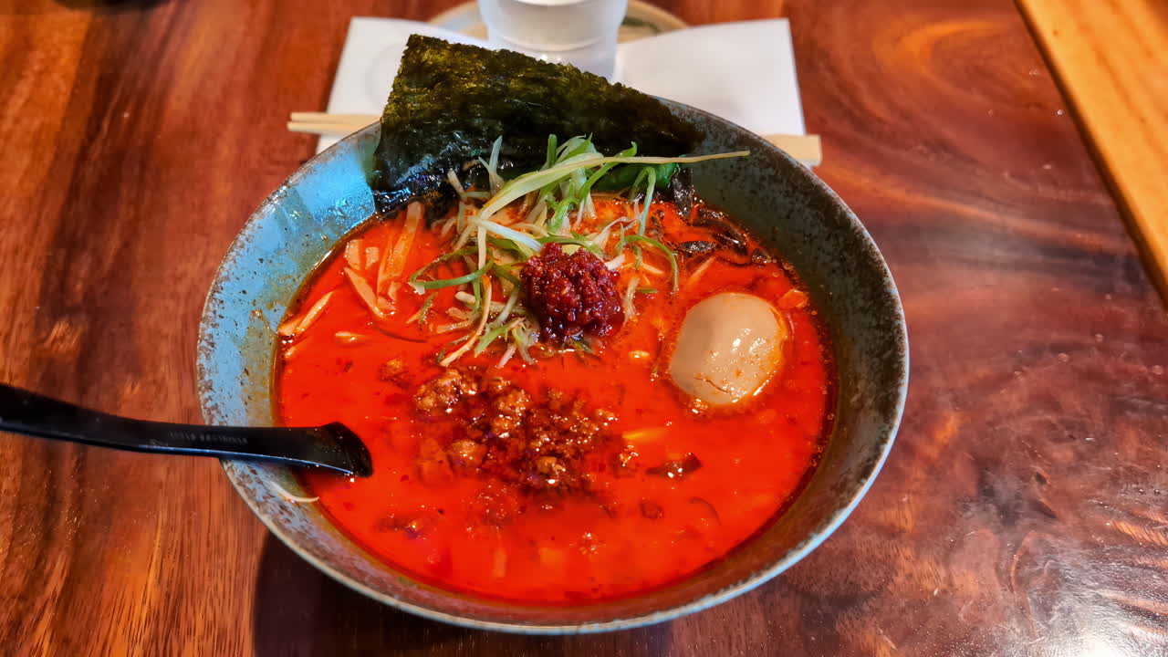 un plato de ramen picante rojo en una hermosa mesa de madera