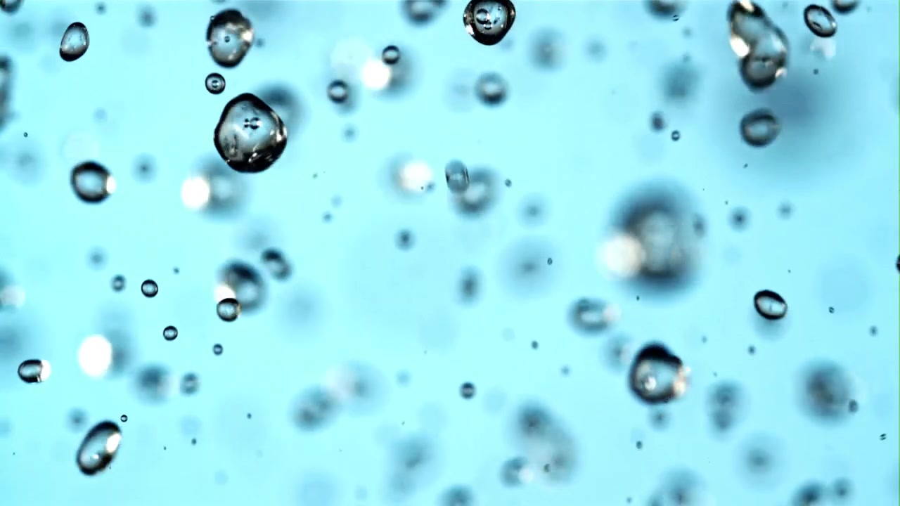 Goccioline d'acqua che cadono al rallentatore su uno sfondo blu