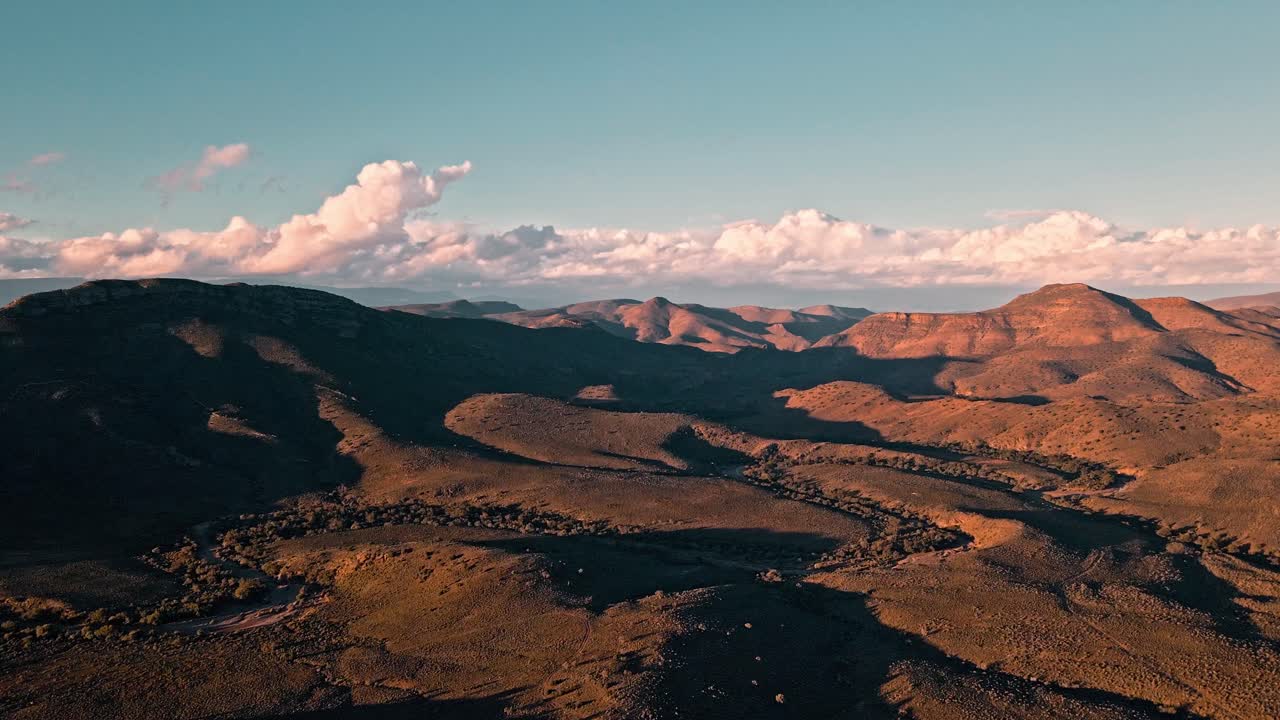 tomada de avión no tripulado del vasto klein karoo en sudáfrica al atardecer con nubes de tormenta en la distancia proporcionando la lluvia muy necesaria para el paisaje estéril y el terreno montañoso accidentado