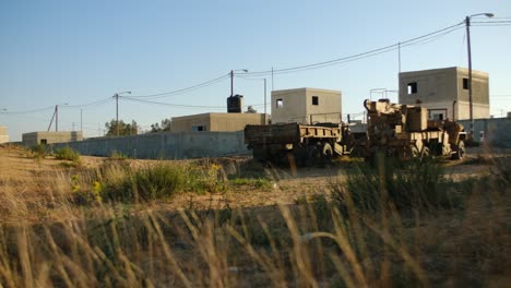 Ein-Wüstengebiet-In-Der-Nähe-Einer-Palästinensischen-Stadt-Mit-Resten-Von-Militärlastwagen,-Die-Auf-Einem-Feld-Liegen