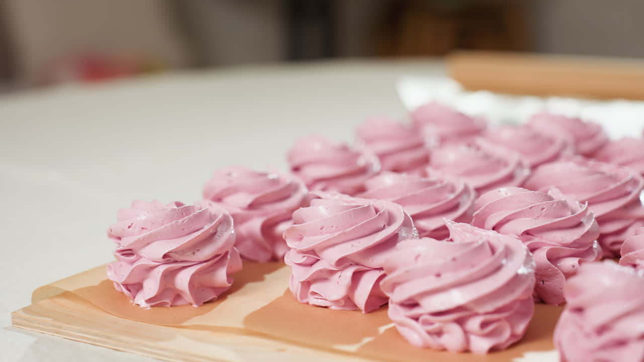Display of beautifully arranged swirl pink cupcakes on brown baking paper with soft natural lighting and slightly blurred background in cozy kitchen setting