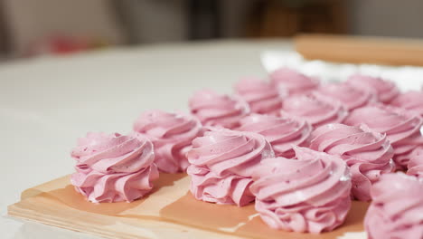 display of beautifully arranged swirl pink cupcakes on brown baking paper with soft natural lighting and slightly blurred background in cozy kitchen setting