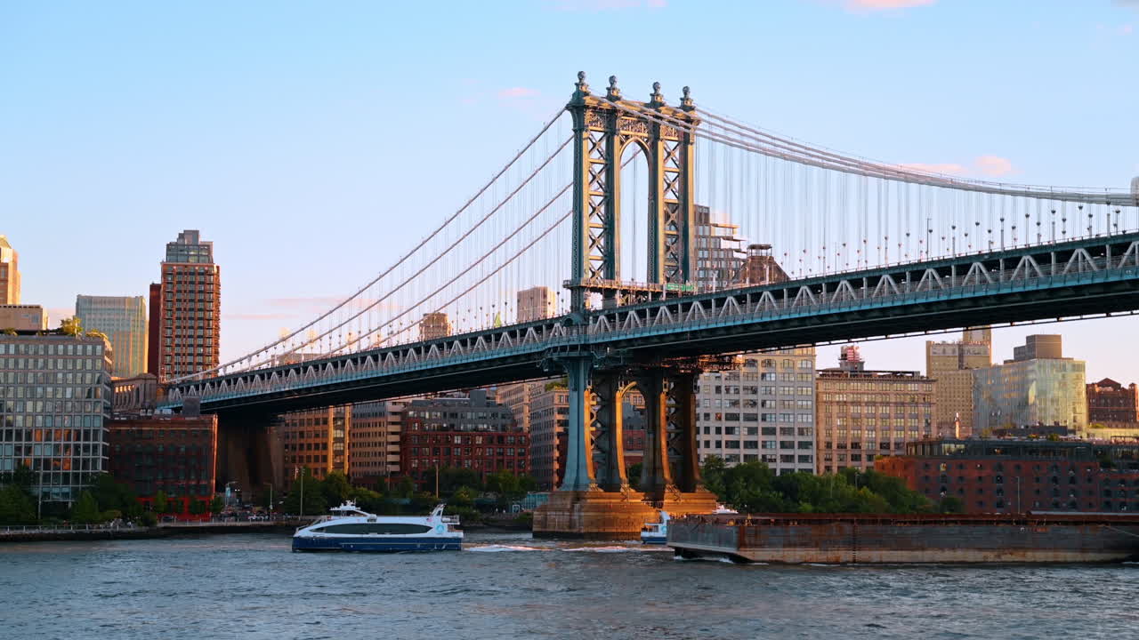 Due traghetti blu e bianchi navigano sotto il Ponte di Manhattan. Barche passeggeri sull'East River con ponte sospeso e lo skyline di New York sullo sfondo.