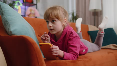 young girl using a phone on a couch