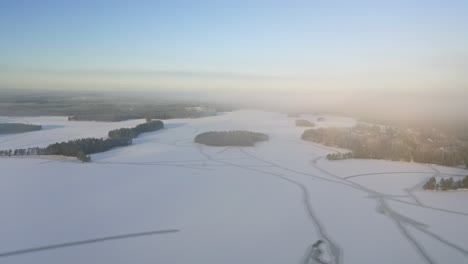 Vista-Aérea-En-Movimiento-Hacia-Adelante-Sobre-El-Lago-Congelado-Con-Islotes-Forestales-Y-Patrones-De-Líneas-Naturales-En-El-Hielo