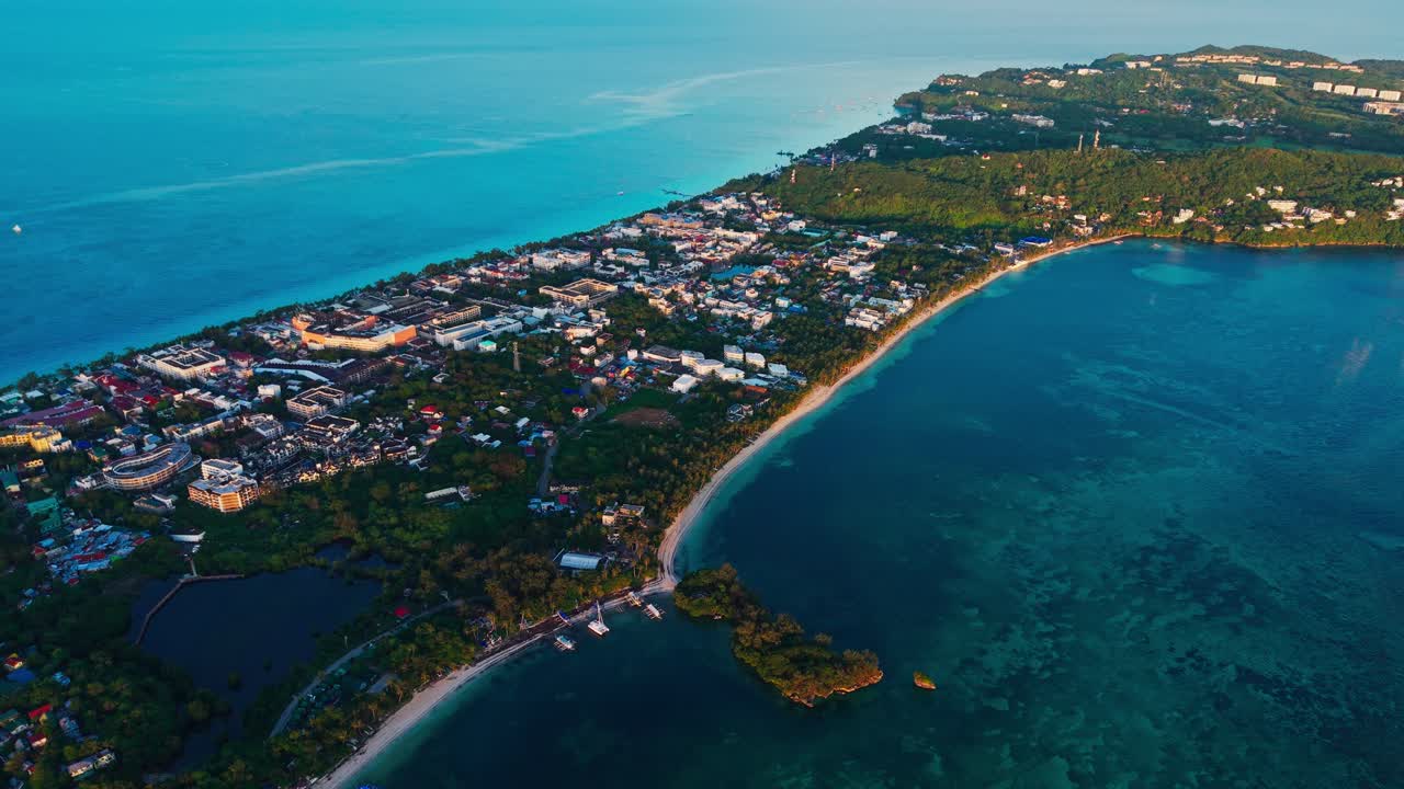 Drone che si allontana e sale, rivelando l'oceano blu e la città costiera di Boracay, Filippine.