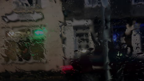 view of street traffic through car windscreen at night when raining, static shot