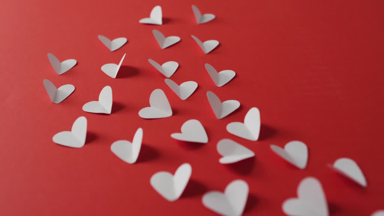 Pink paper hearts on red background at valentine's day