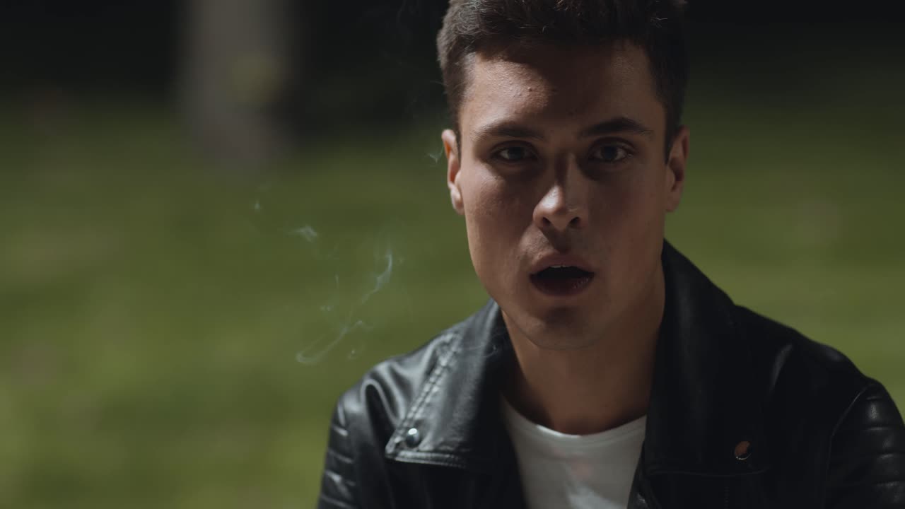 joven fumando al aire libre por la noche