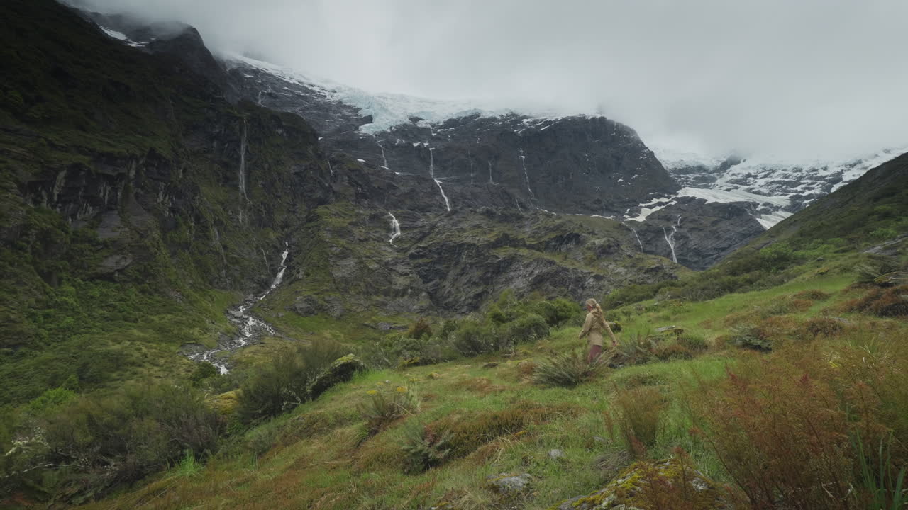 mujer caminando por el verde valle alpino con espectaculares montañas altas