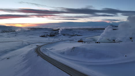 White-steam-comes-from-one-of-the-chimneys-of-a-geothermal-plant-in-the-snowy-Icelandic-landscape-after-sunset