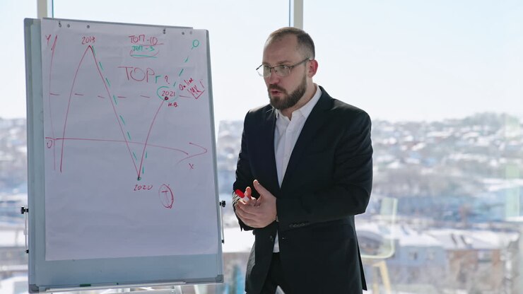 Emotional speech in front of the colleagues at the meeting. Businessman standing in front of the flip chart presents the infographics. Cityscape blurred at the backdrop.