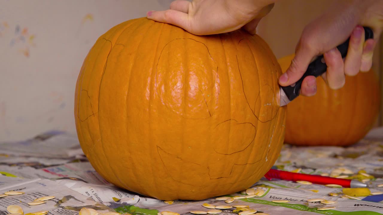 calabaza carvin hembra cortando la linda cara de jack o'lantern en calabaza con un cuchillo preparándola como decoración de halloween