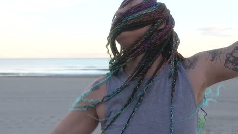 woman with colorful braids dancing with his hair moving on the beach