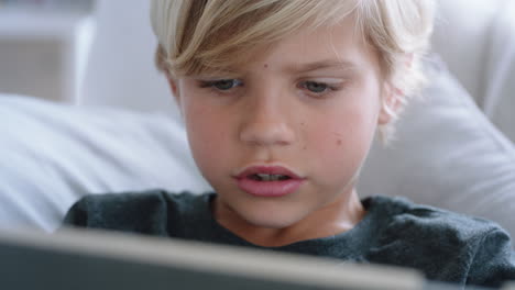 happy little boy using digital tablet computer playing game relaxing on sofa at home child browsing online with mobile device technology anti social addiction concept 4k