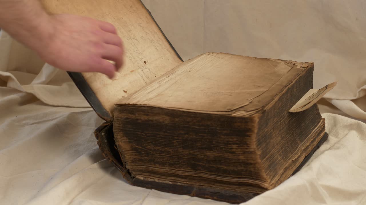 착용된 오래된 무거운 성경을 여는 남성 손의 닫기 슬로모 슬라이드 샷