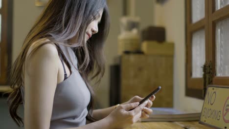 las mujeres asiáticas juegan al teléfono en una cafetería.