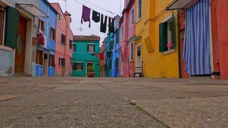 slow motion ground surface pov of burano colorful houses and hanging clothes, italy. first person view