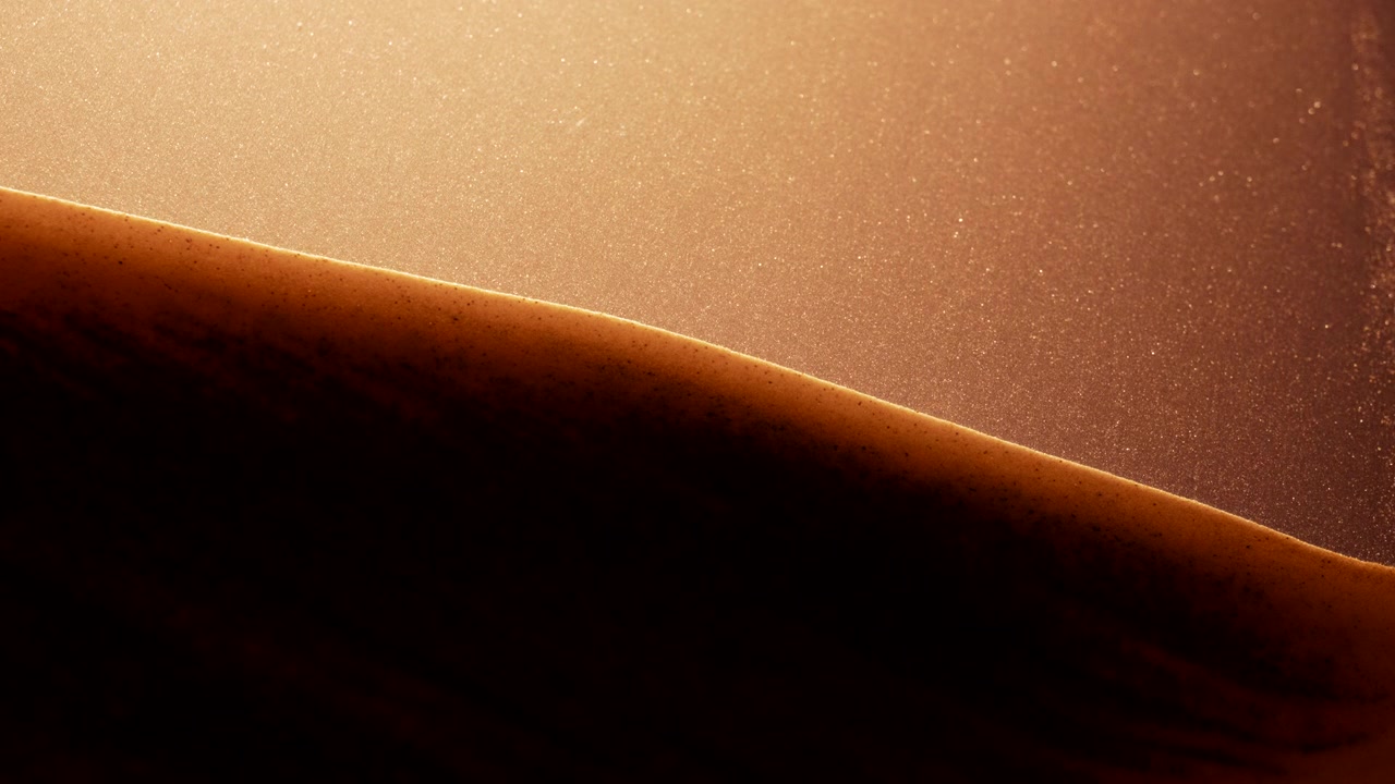 Piccole particelle granulose che galleggiano in slow motion astratto.