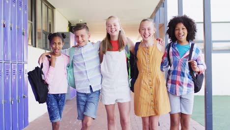 portrait of happy diverse schoolchildren at locker in school