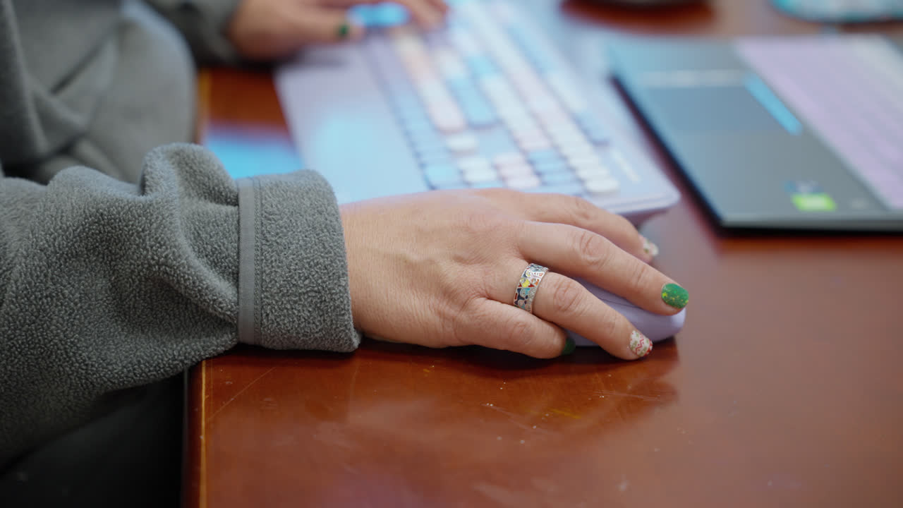 Right handside hands interacting with digital laptop device on office desk holding and scrolling with mouse