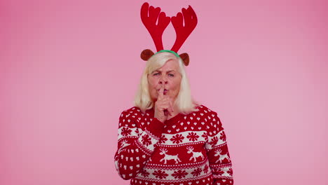 Senior-old-woman-in-Christmas-sweater-presses-index-finger-to-lips-makes-silence-gesture-sign-secret