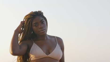 african swimwear model playing with her braids while posing in a bikini top