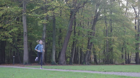 Toma-Dinámica-De-Una-Mujer-Corriendo-Hacia-La-Cámara-En-Un-Campo-De-Hierba-En-El-Parque