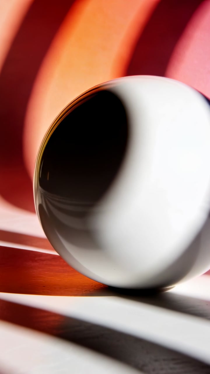 Vertical video: Glossy sphere rolling from tilt on striped table showing glints, shadows for design