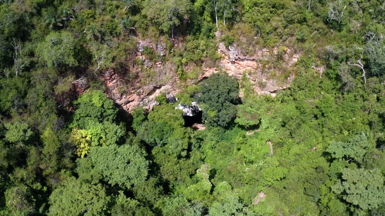 tiro aéreo ascendente de la entrada de la cueva al pozo encantado o poço encantado rodeado de árboles tropicales, plantas y acantilados en el parque nacional chapada diamantina en el norte de brasil